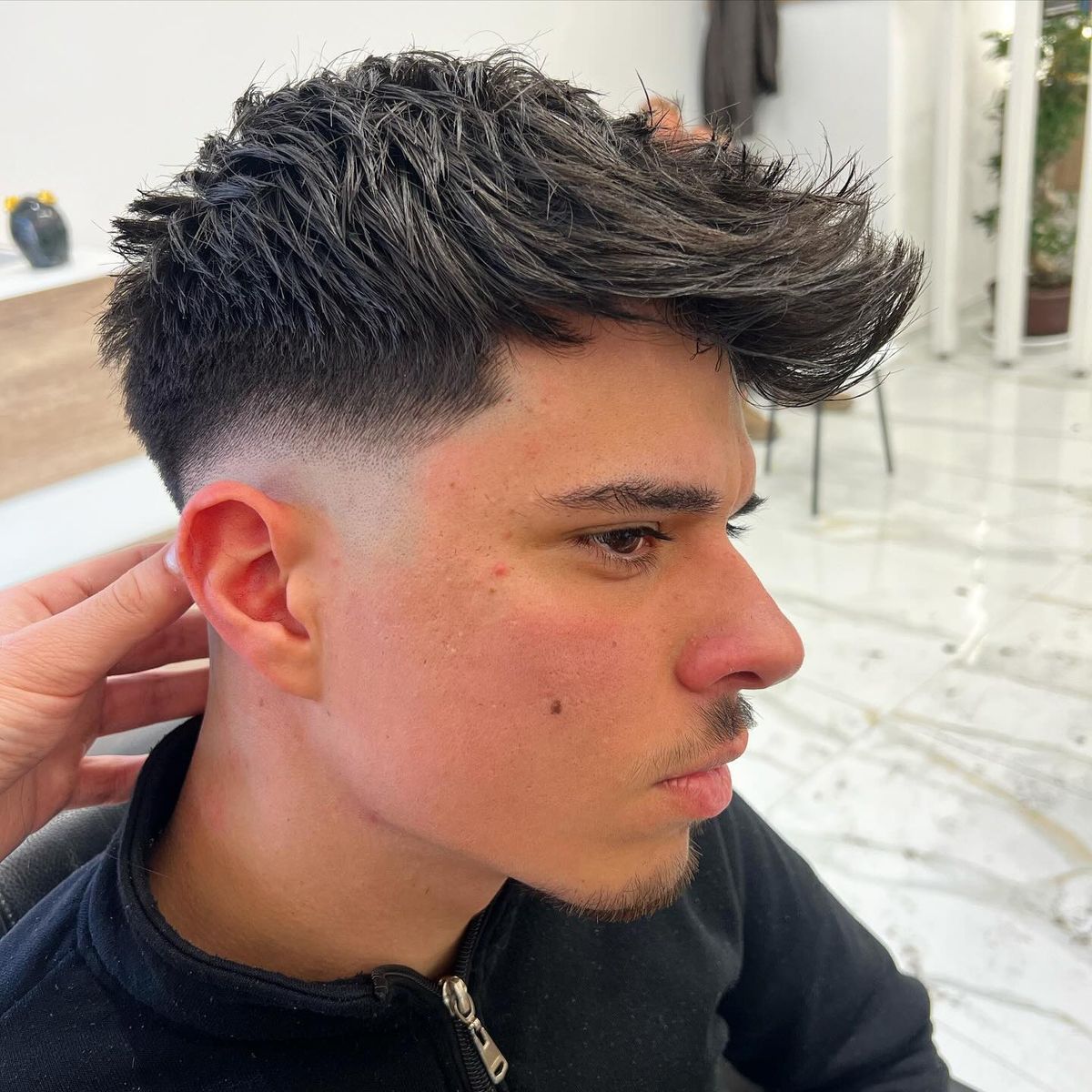 Low fade e ciuffo spettinato portato di lato, di profilo